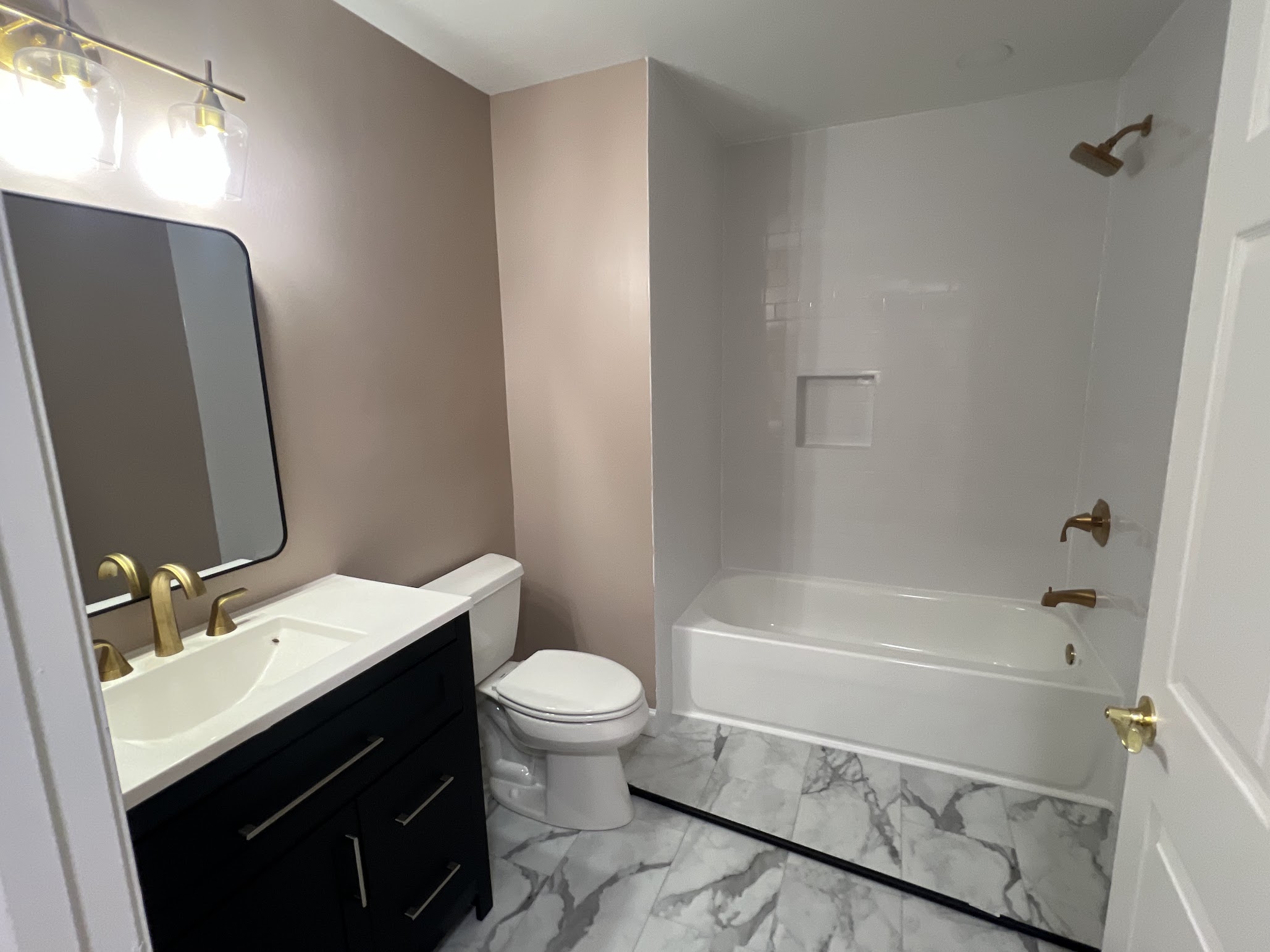 Completed bathroom with a tiled tub surround, vanity, mirror, and finished flooring