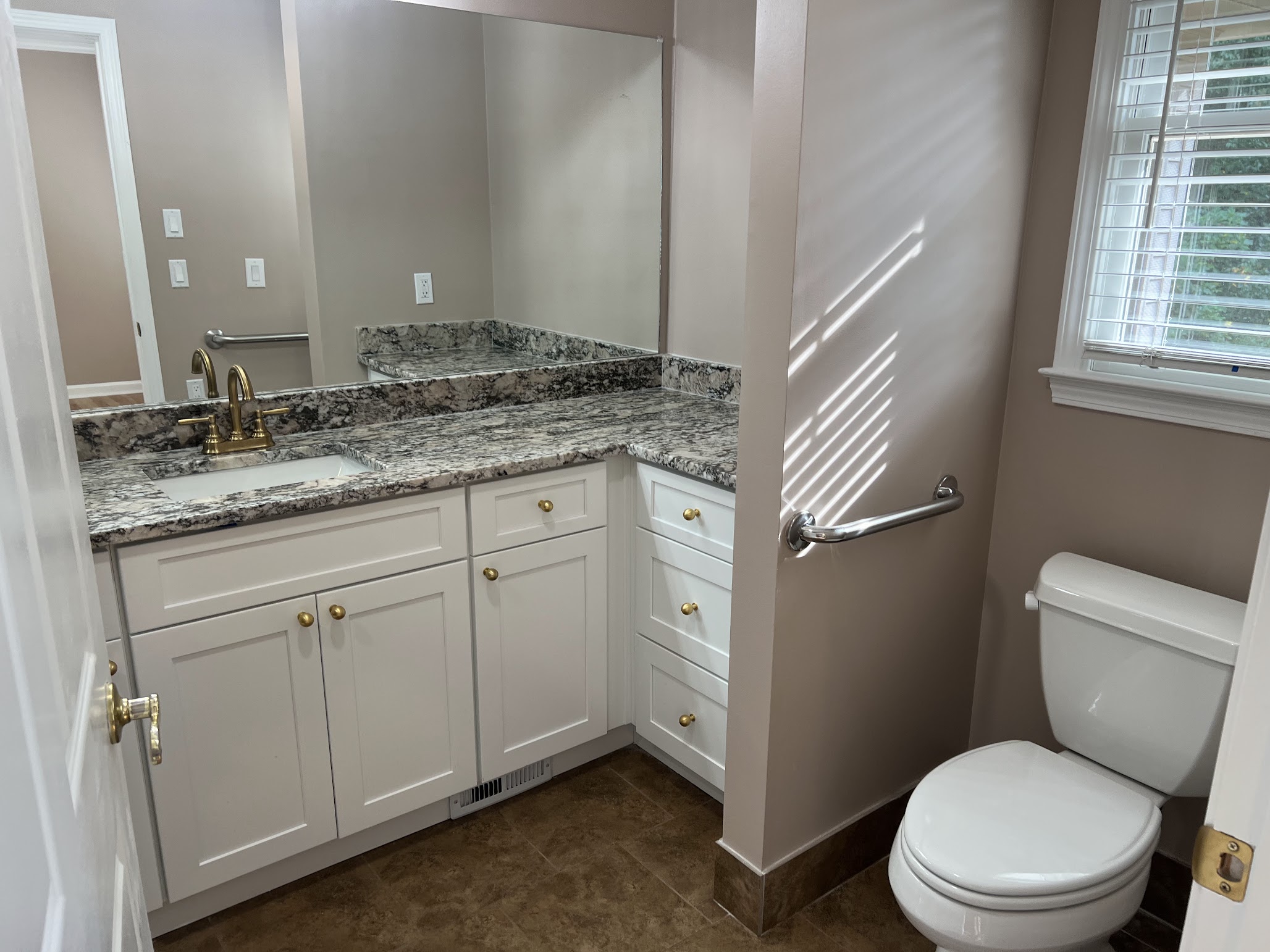 Completed bathroom vanity with white cabinetry, stone countertop, mirror, and finished wall surfaces