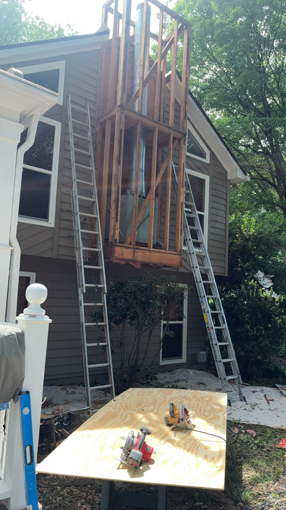 Exterior chimney enclosure during repair, with siding removed and wood framing exposed