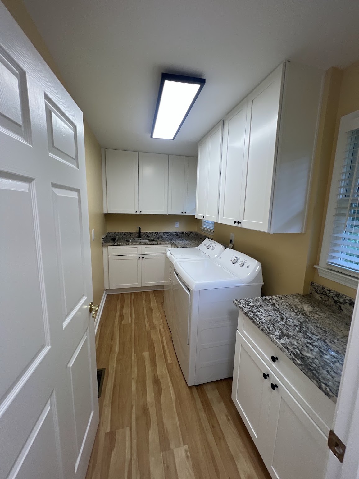 Completed laundry room with white cabinets, stone countertops, a sink, washer, and dryer
